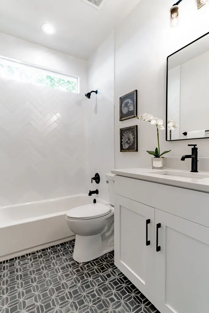 Full bathroom remodel with white herringbone tile surround and patterned floor tile in San Antonio