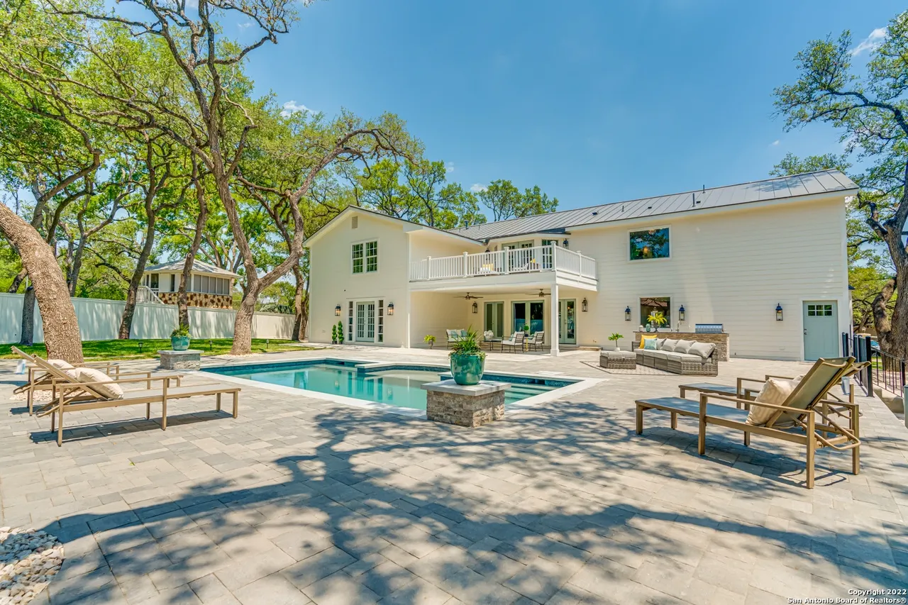 Castle Hills Manor backyard remodel with pool, patio lounge chairs, covered porch outdoor living area, and mature oak canopy in San Antonio TX