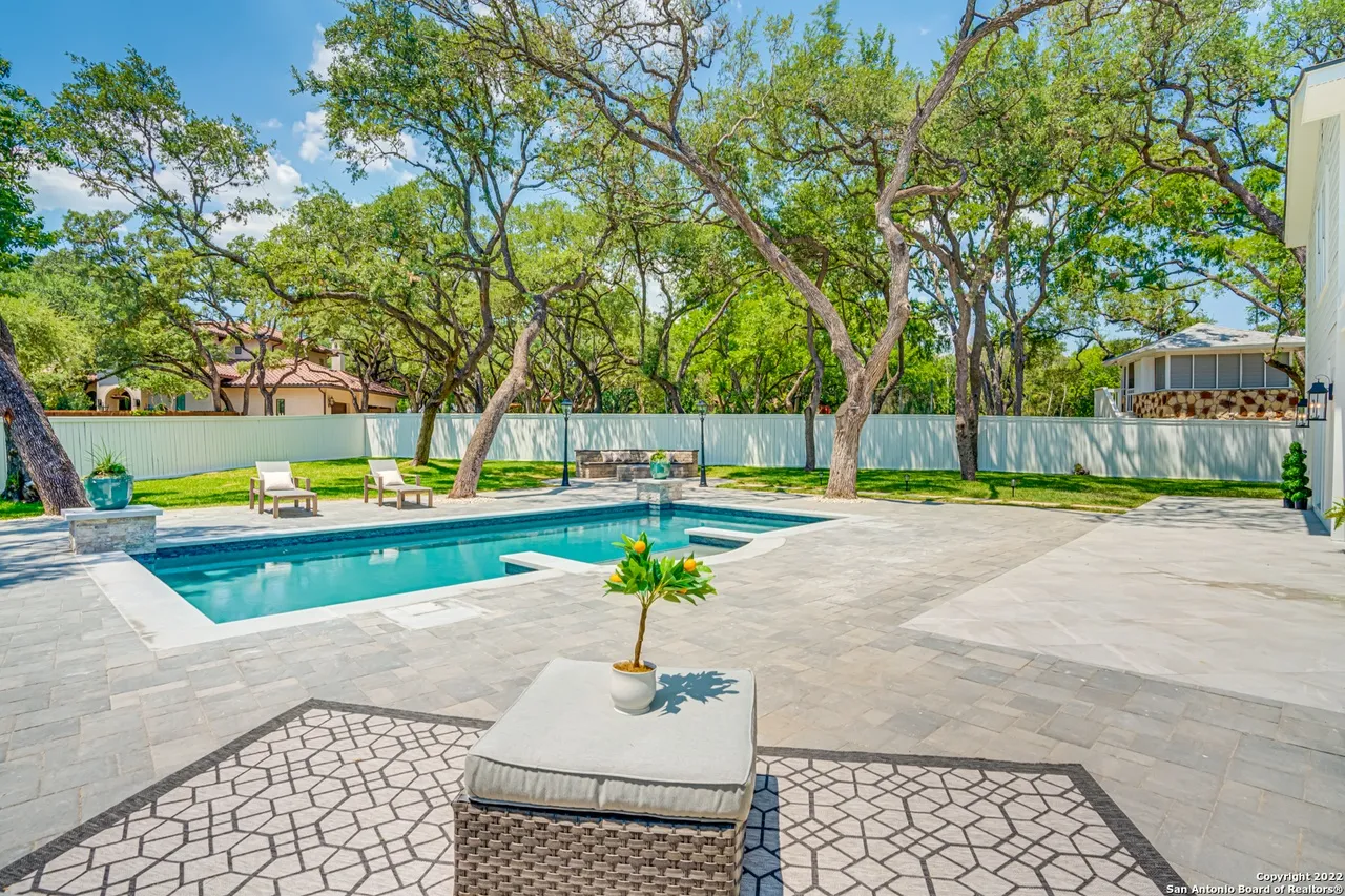 Castle Hills Manor backyard pool and spa remodel with travertine pavers, lounge chairs, and mature oak trees in San Antonio TX