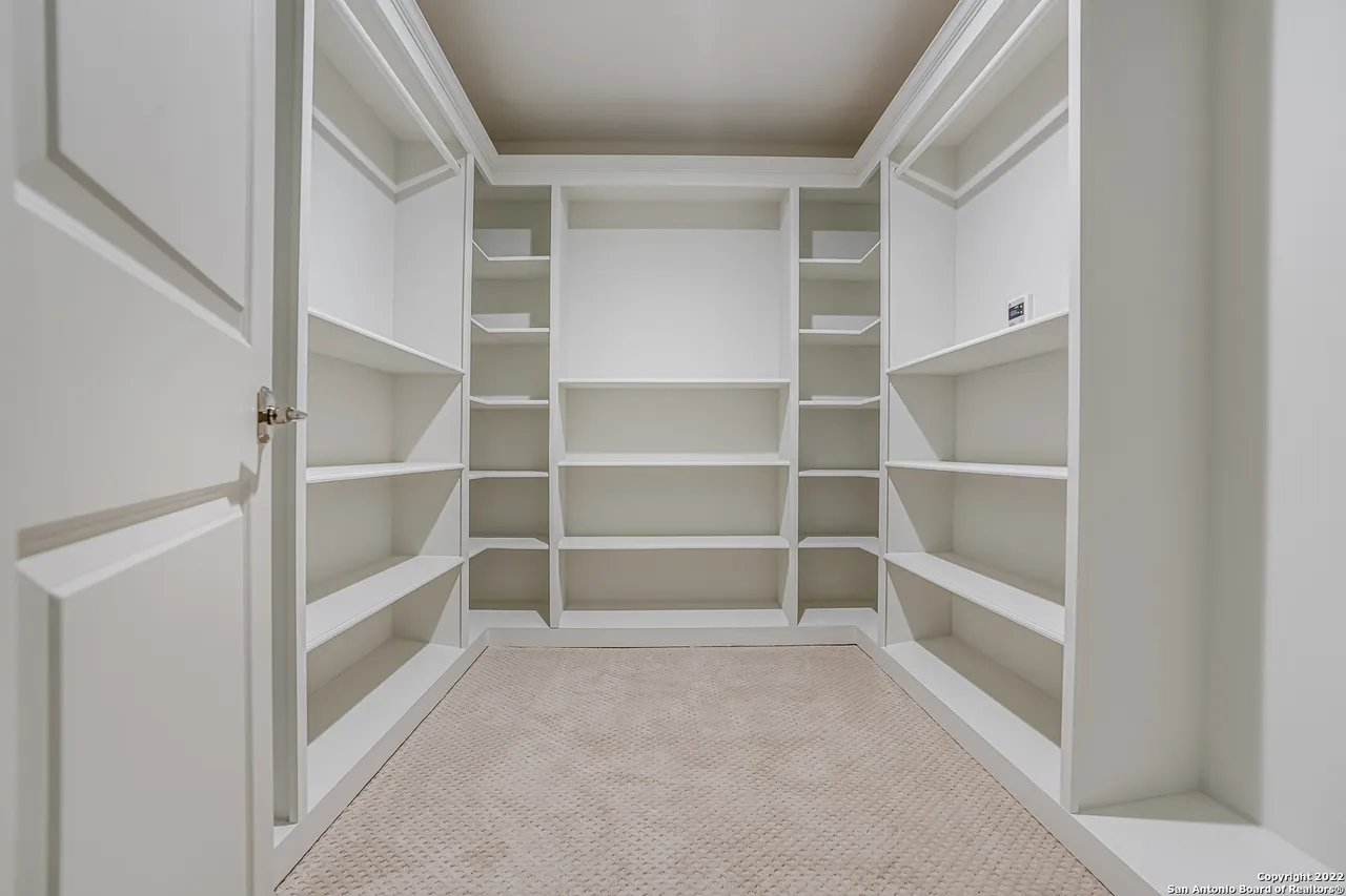 Custom walk-in closet remodel with floor-to-ceiling built-in white shelving in Castle Hills San Antonio TX