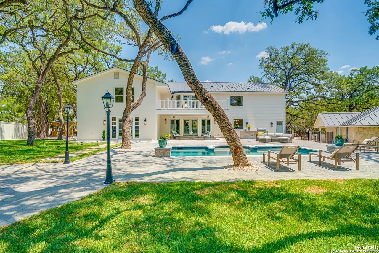 Castle Hills Manor backyard remodel with pool, stepping stone path, manicured lawn, stone lantern posts, and mature oak trees in San Antonio TX
