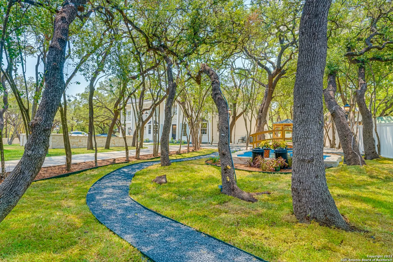 Castle Hills estate landscaping remodel with winding gravel path through mature live oak trees leading to pool area in San Antonio TX