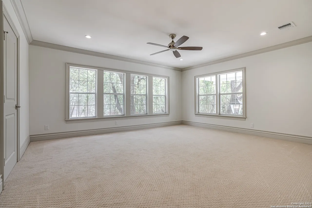 Spacious guest bedroom remodel with carpet, crown molding, ceiling fan, and abundant natural light in Castle Hills San Antonio TX