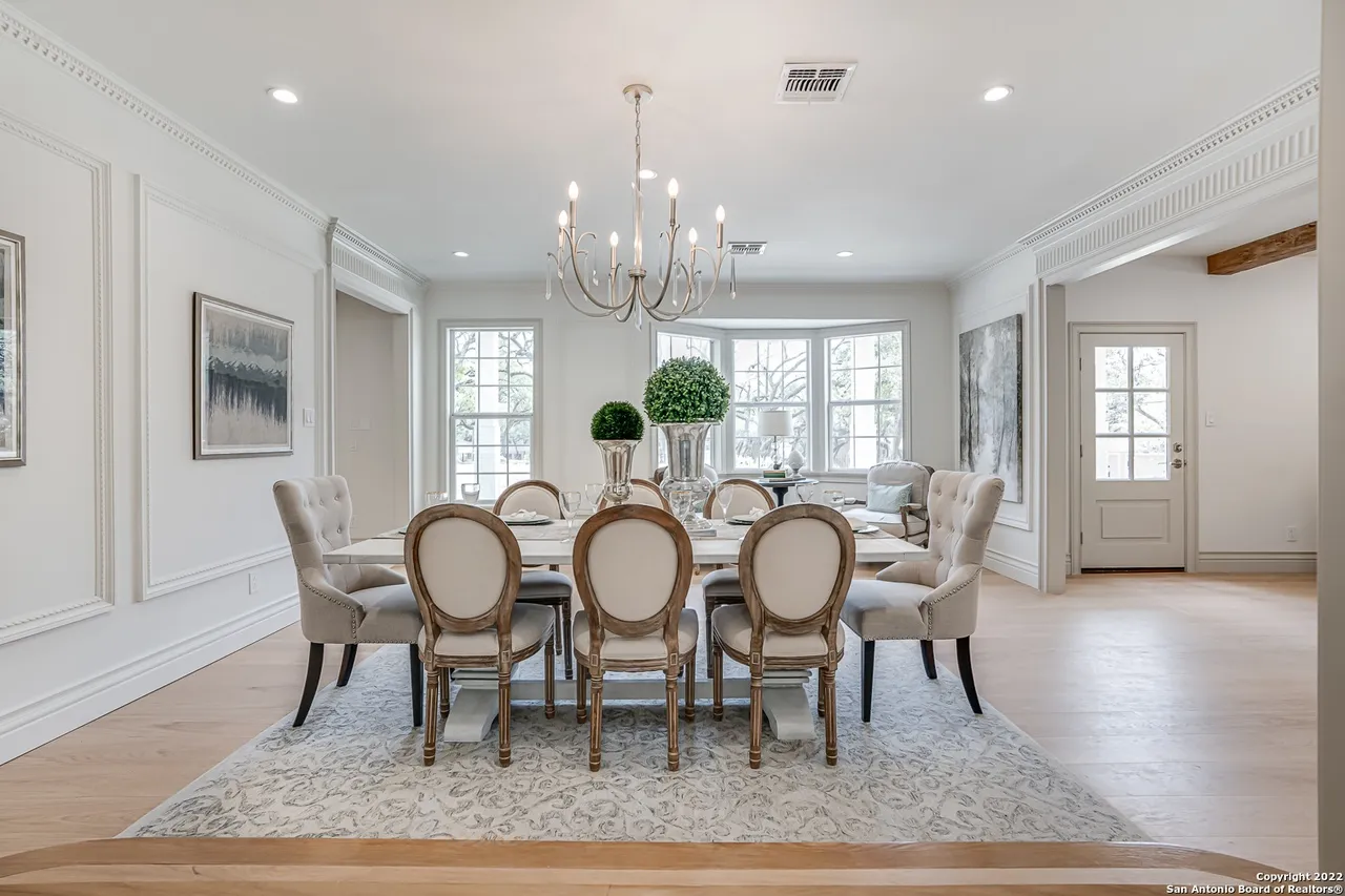 Elegant formal dining room remodel with chandelier, crown molding trim, and bay window in Castle Hills San Antonio TX