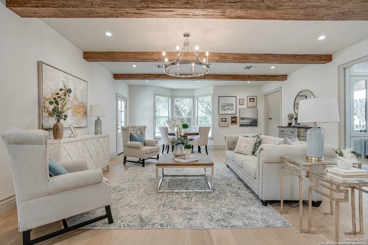 Remodeled living room with reclaimed wood beam ceiling, round chandelier, and European white oak floors in Castle Hills San Antonio TX