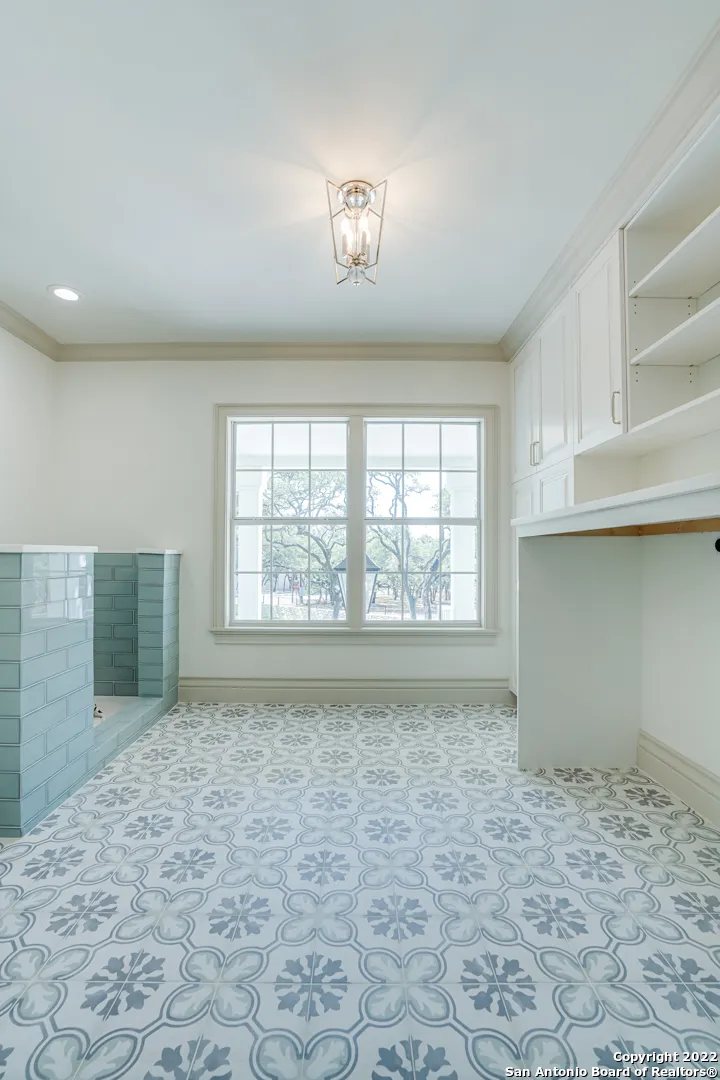 Remodeled utility room with custom dog bath station, decorative encaustic tile floor, and built-in white cabinetry in Castle Hills San Antonio TX