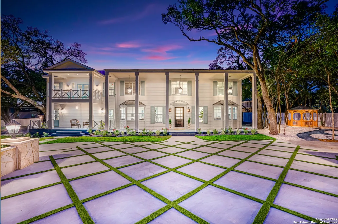 Castle Hills Manor exterior remodel with grand motor court pavers and landscaping at dusk in San Antonio TX