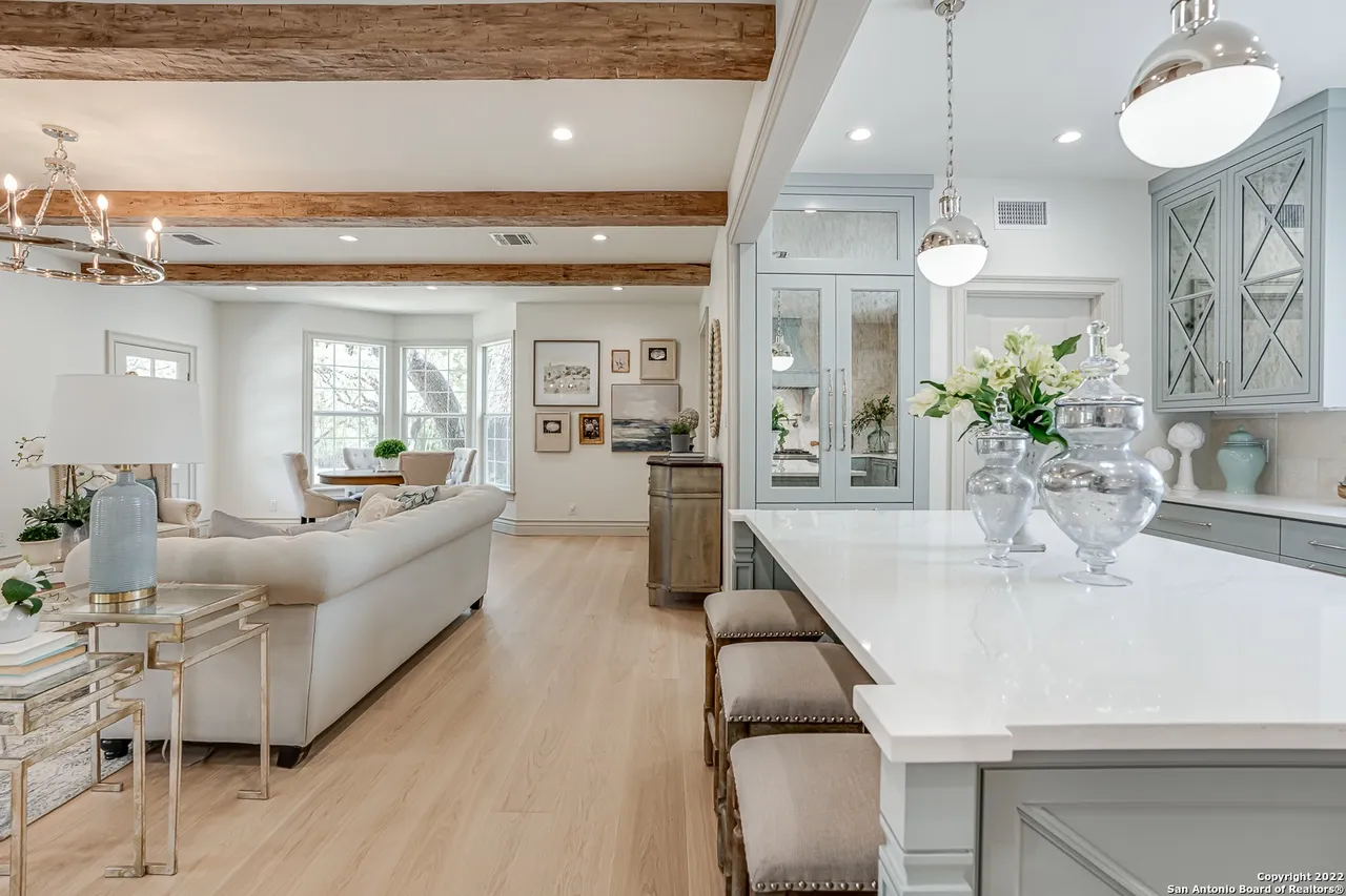 Open concept kitchen and living room remodel with reclaimed wood beams, quartz island, and European white oak floors in Castle Hills San Antonio TX