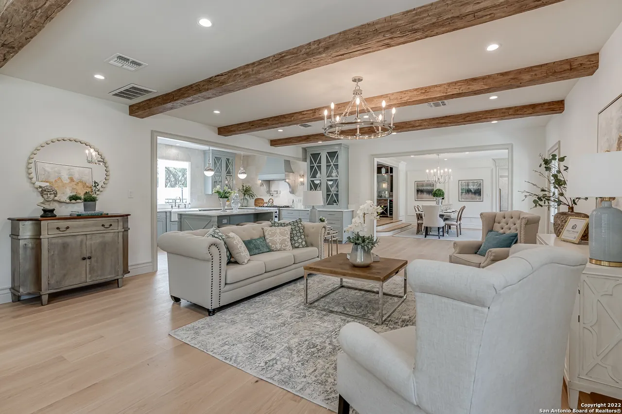 Open concept living room and kitchen remodel with reclaimed wood beams and sage blue-gray cabinetry in Castle Hills San Antonio TX