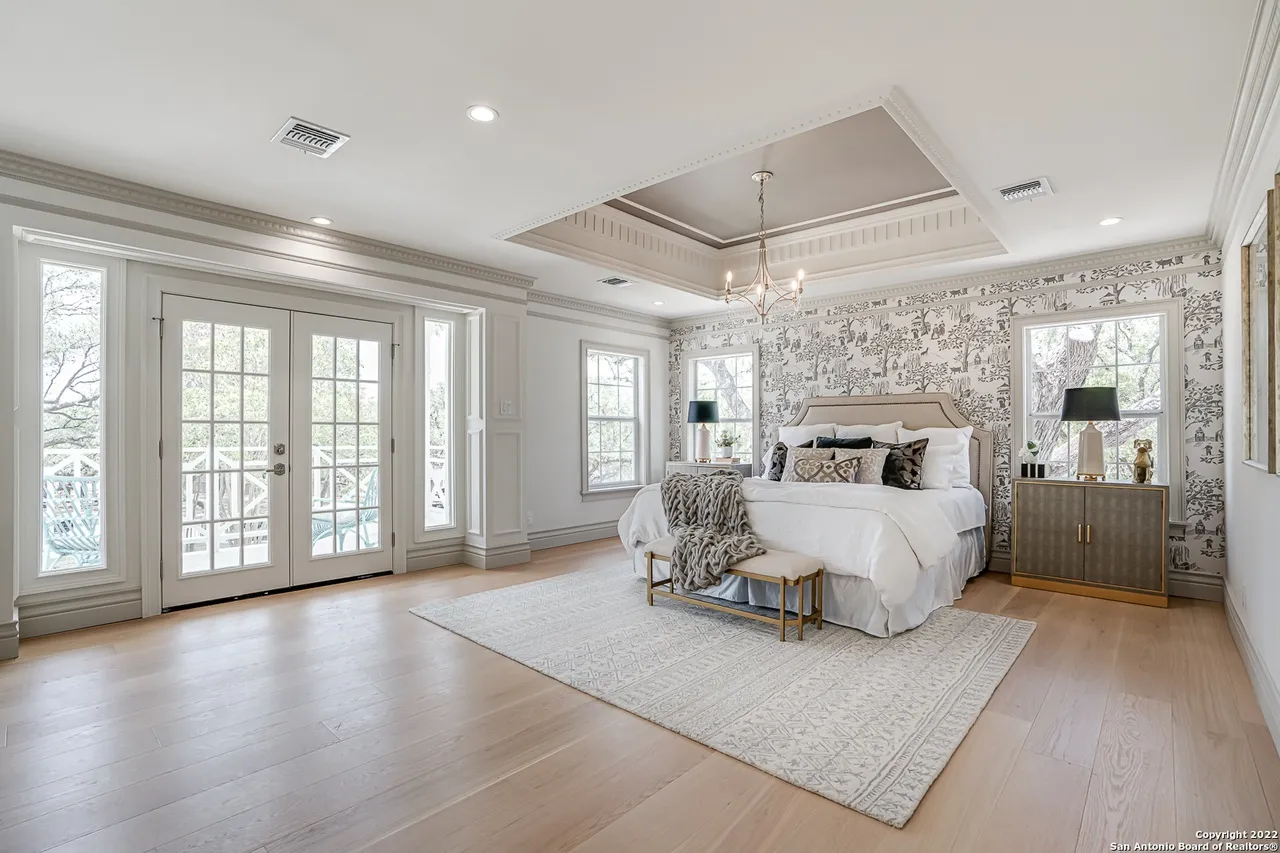Primary bedroom remodel with coffered tray ceiling, decorative crown molding, toile wallpaper accent wall, and balcony access in Castle Hills San Antonio TX