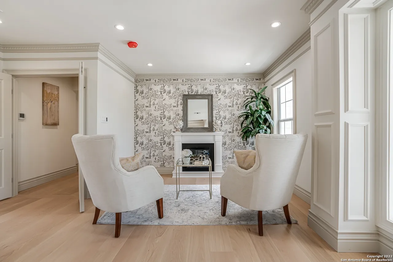 Primary bedroom sitting area remodel with fireplace, toile wallpaper accent, and panel wall molding in Castle Hills San Antonio TX