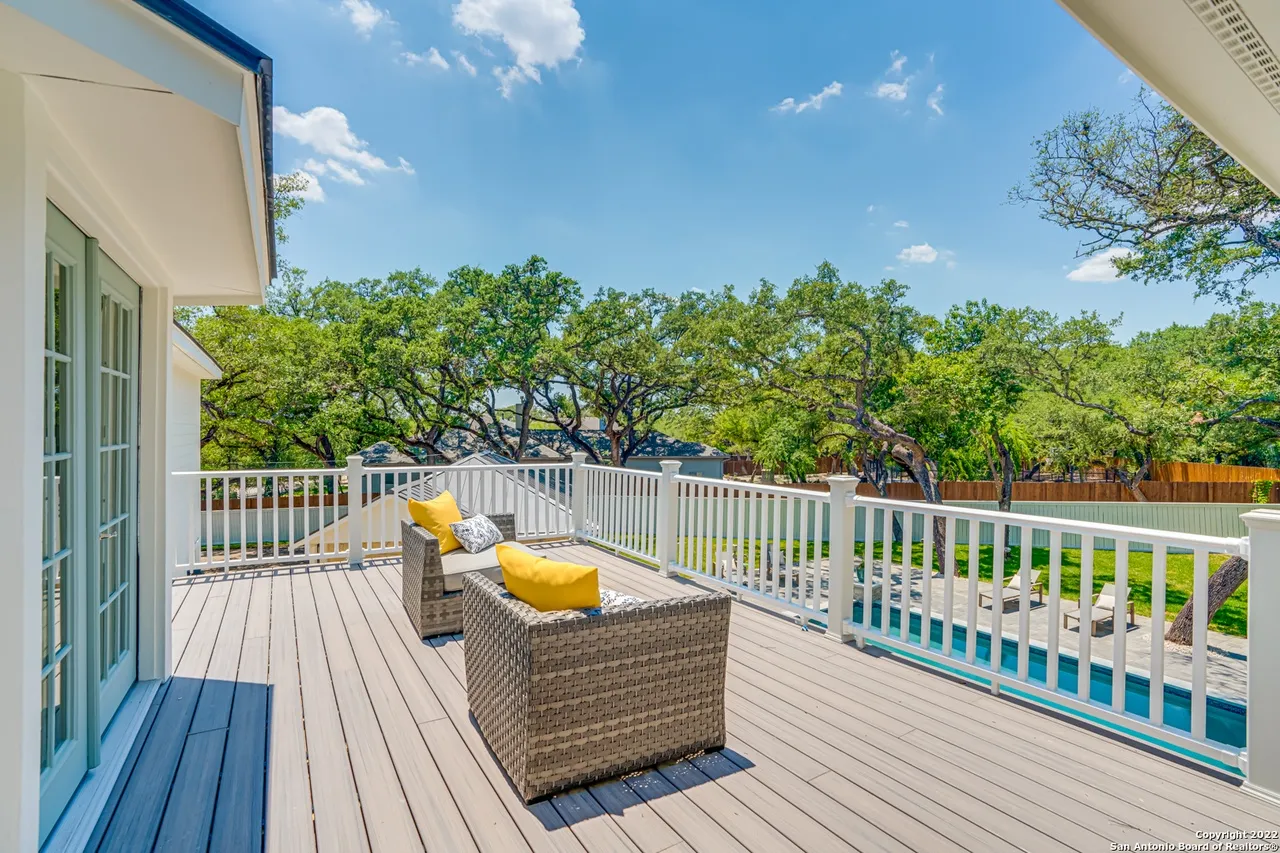 Remodeled second-story deck and balcony with wicker seating, yellow accent pillows, and pool view at Castle Hills Manor in San Antonio TX