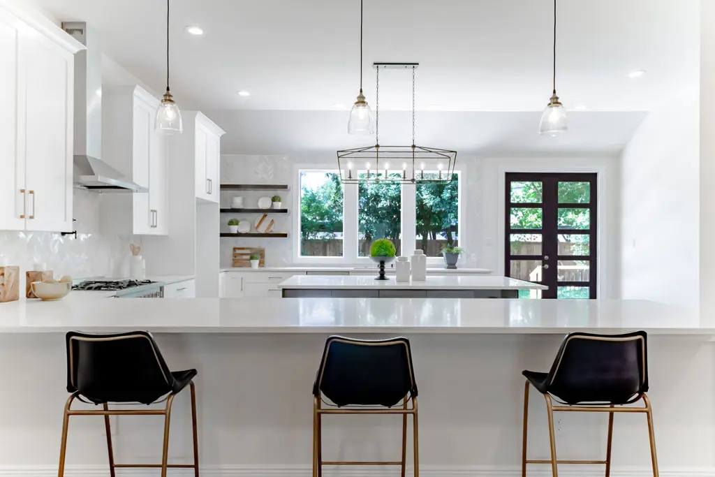 Modern white kitchen renovation with island seating and pendant lighting in San Antonio TX