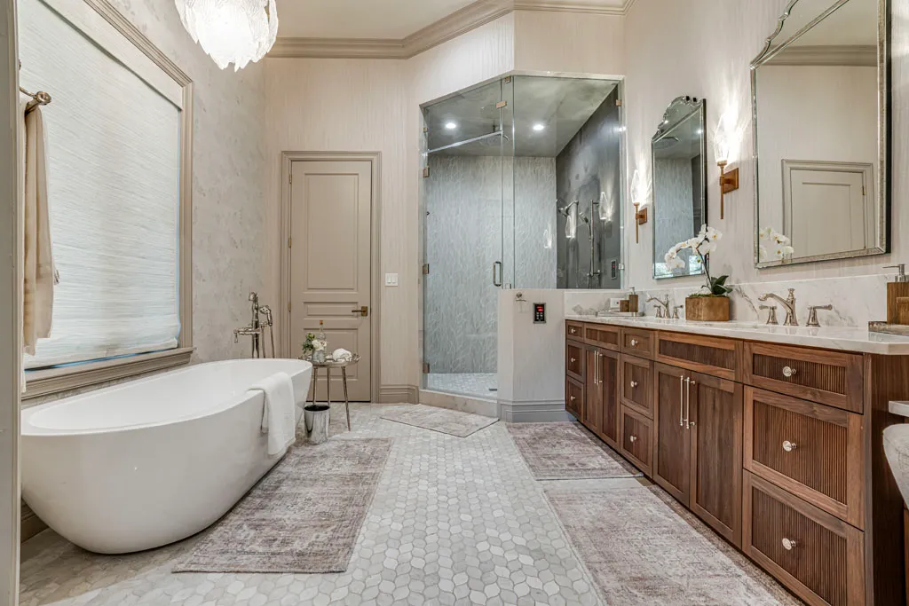 Completed luxury master bathroom remodel featuring freestanding soaking tub, frameless glass shower, and custom walnut vanity in San Antonio TX