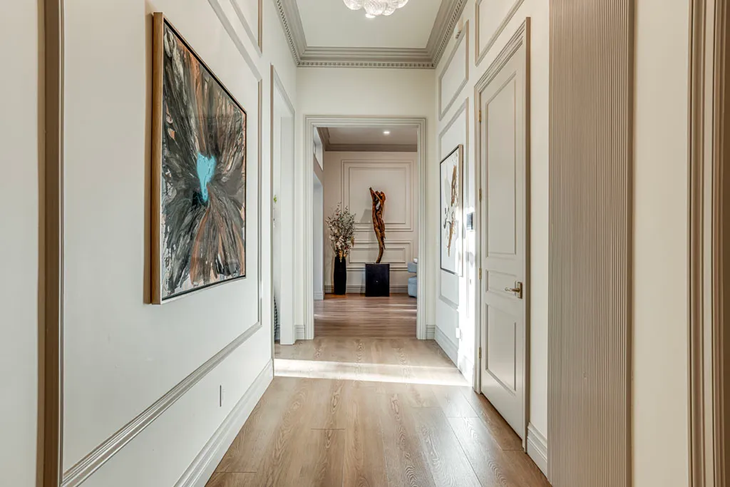 Beautifully renovated hallway featuring wainscoting, crown molding, wide-plank oak floors, and gallery wall in San Antonio TX