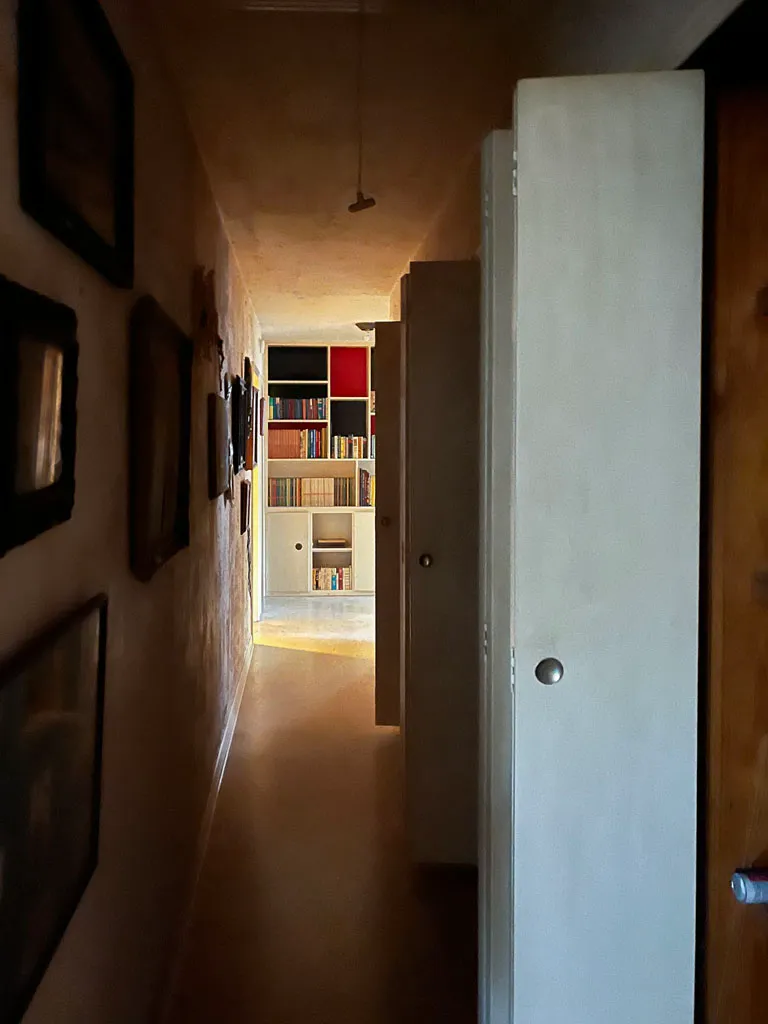 Dim, cramped hallway with dated walls and worn flooring before renovation in San Antonio TX