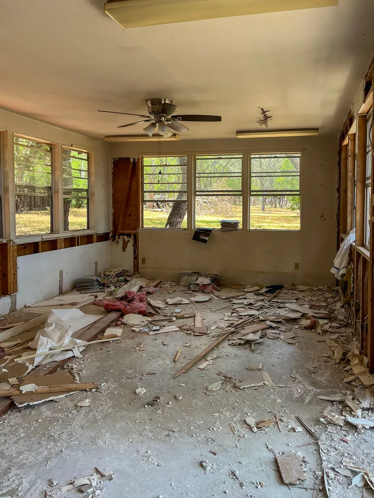 Sunroom during demolition phase with exposed walls and debris before remodel in San Antonio TX